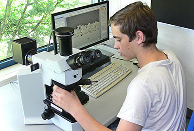 Person überprüft eine Probe am Mikroskop