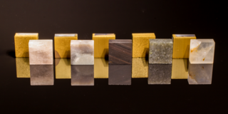 Gesteinseinsätze mit und ohne TiN-Beschichtung (von links nach rechts: Silberquarzit, Feuerstein, lamellarer Obsidian, Alta-Quarzit, Quarz)